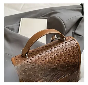 Detail showing the brown woven leather texture and sturdy handle of the commuter handbag