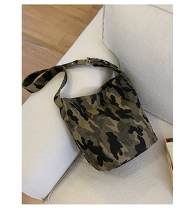 Detail of adjustable metal buckle and forest camouflage canvas fabric on large tote bag