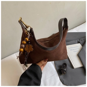 Detail of dark brown suede shoulder bag with beaded charm and gold-toned zipper hardware
