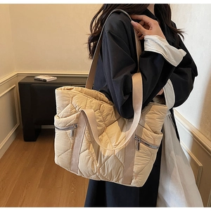 Detail of a beige quilted tote bag showing large capacity and diamond stitch pattern