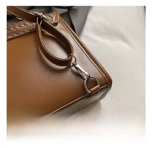 Close-up of premium silver metal hooks and woven strap details on a brown PU leather bag