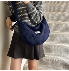 Detail of heart-shaped quilted navy crossbody bag showing fluffy puffy texture and strap
