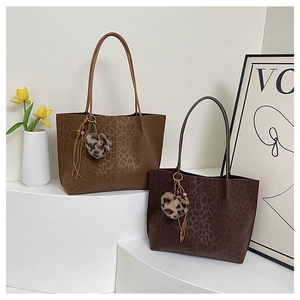 Detail of large leopard print tote bags in brown faux leather with heart tassel charms