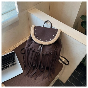 Detail of vintage brown suede backpack featuring long fringe and silver star stud accents