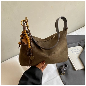Detail of vintage brown suede shoulder bag with decorative wooden beads and clover charm