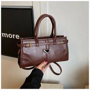 Detail of dark brown lychee texture leather handbag with golden buckle and metal plate