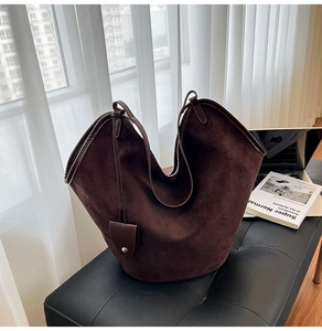 Detail of a large vintage dark brown suede tote bag with decorative buckle on a bench