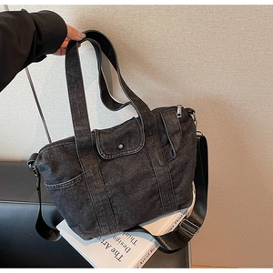 Detail of black denim tote bag with adjustable shoulder strap and silver metal hardware
