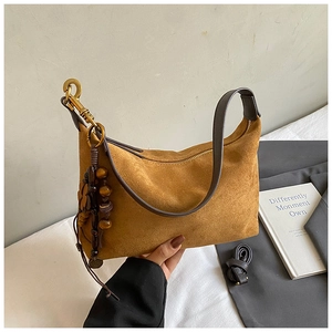 Detail of tan faux suede dumpling bag with leather strap and wooden bead tassel