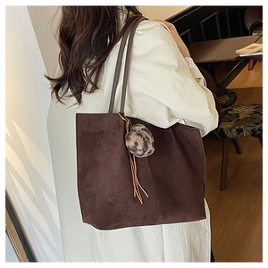 Detail view of large dark brown suede tote bag with leopard fur ball and leather tassels