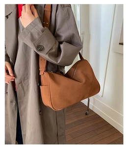 Braune matte Ledertasche an Modell getragen über grauem Mantel für den Freizeit-Look