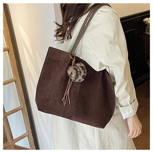 Detail of brown suede tote bag with leopard print pom-pom charm and slim shoulder strap