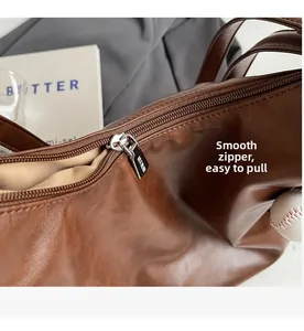 Close-up of smooth metal zipper on brown leather tote bag with baseball charm detail