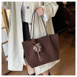 Brown suede tote bag with leopard print pompom detail shown in a cafe setting