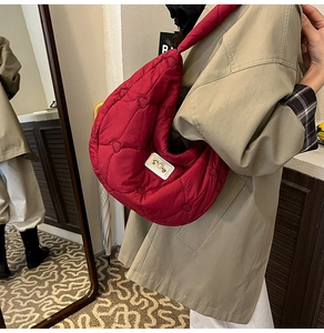 Detail of red quilted heart pattern puffer crossbody bag with decorative Story label