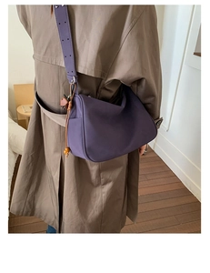 Detail der lila Leder-Satteltasche mit Holzperlenfransen und breitem Schultergurt-Design