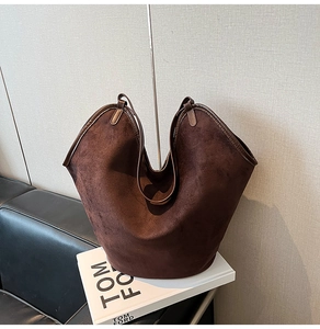 Detail view of large dark brown suede tote bag featuring smooth leather handles