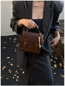 Close-up of brown woven texture bag with silver buckles and elegant beaded charm detail