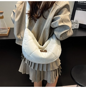 Detail of white moon crossbody bag featuring heart quilted patterns and brown leather patch