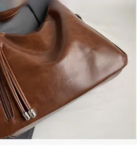 Close-up of brown vintage leather tote with silver zipper and brand lettering detail