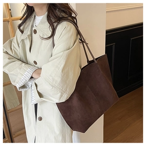 Detail of dark brown suede tote bag styled with beige trench coat for office commute