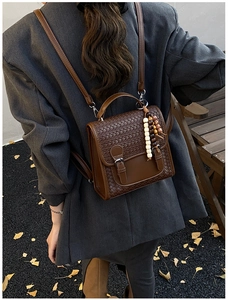 Outdoor shot of a vintage brown woven backpack with leather strap and bead charm