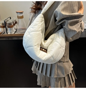 Detailed view of white quilted hobo bag featuring heart embroidery and side carry style