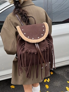 Bohemian brown suede backpack with fringe and star studs shown in an outdoor side view