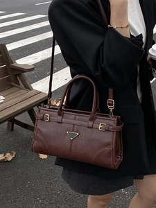 Classic dark brown pebbled leather satchel with signature triangular hardware in a street style