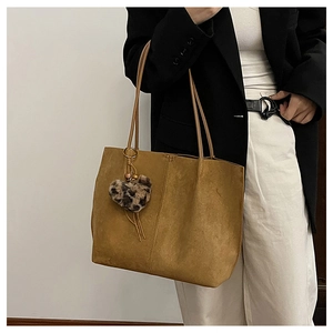 Detail of brown suede tote bag with decorative leopard print heart charm for women