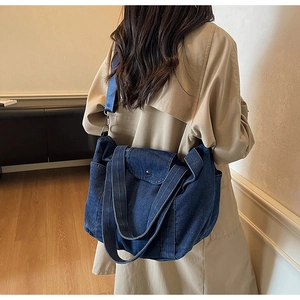 Detail of large denim tote bag featuring adjustable strap and premium washed texture