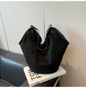 Detail of black suede tote bag with wavy opening and slim straps for office work