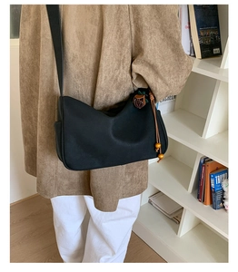 Detail der schwarzen matten Wildleder-Schultertasche mit Blumenanhänger und Holzperlen