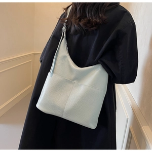 Seitenansicht des Modells mit großer hellblauer Ledertasche mit Litschimuster und Schultergurt