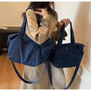 Detail of dark blue denim tote set featuring metal buckle pocket and adjustable straps