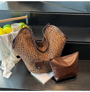 Detailed view of leopard print tote bag set with a matching brown zip pouch on a wooden shelf