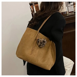 Detail of camel suede tote bag with leopard heart pompom and tassel charm accessory