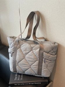 Quilted grey tote bag with rhombus pattern and metal zippers in a casual lifestyle setting