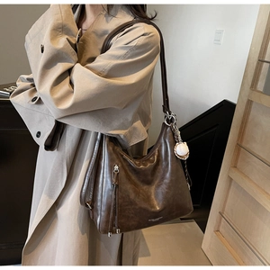 Detail of dark brown vintage hobo bag with decorative zipper and baseball charm