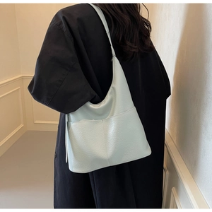 Detailansicht der minzgrünen Sichel-Tasche mit Lychee-Narbenleder an einem Modell