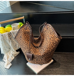 Close-up of leopard print faux suede tote bag with brown leather trim and hanging tag