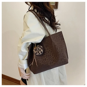 Detail of large leopard print tote bag with fuzzy ball charm and leather tassels