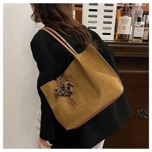 Detail of large brown suede tote bag with leopard print charm on female model