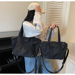Detail view of large and small black denim tote bags with utility pockets and metal rivets