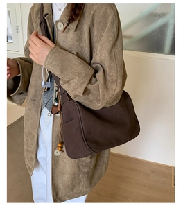 Nahaufnahme der braunen Wildledertasche mit Seitentasche und dekorativer Perlenquaste