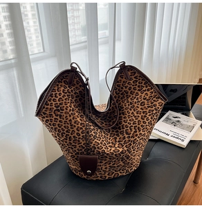 Detail of leopard print suede tote bag with brown leather trim in a cozy office setting