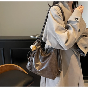 Retro large brown tote bag with woven fringe and brand logo on shoulder of a model