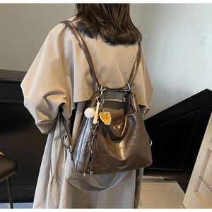 Close-up of a vintage brown leather tote bag with a unique baseball theme charm