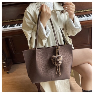 Close-up of leopard print tote bag with plush heart charm in a vintage piano setting