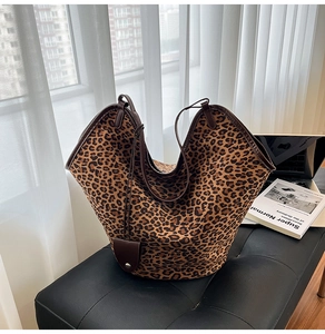 Detail of leopard print tote bag with brown leather trim and hanging leather accessory